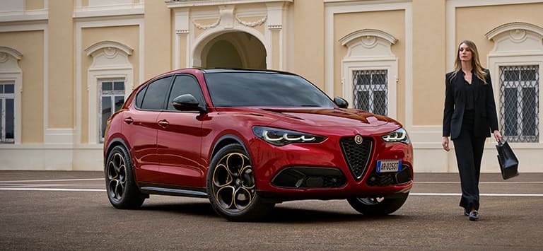 A passenger-side front angle of a European version red 2025 Alfa Romeo Stelvio Intensa.