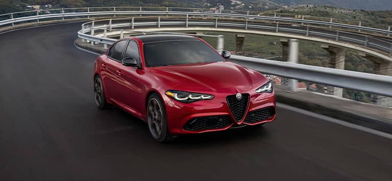 Un Alfa Romeo Giulia Veloce 2026 rojo encarando una curva en una autopista elevada.