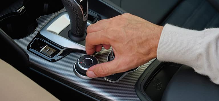 El selector de modo de manejo A.D.N. ubicado en la consola central, junto con el selector de marchas de la transmisión y los controles de radio en el Alfa Romeo Giulia 2026.