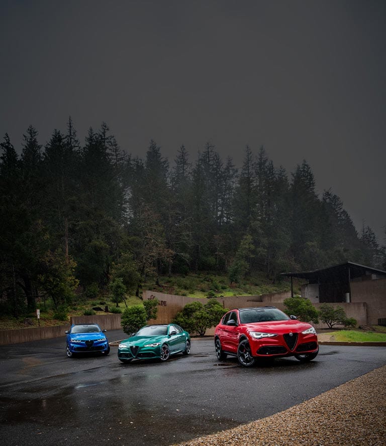 A red 2026 Alfa Romeo Tonale Sport Speciale model parked in a courtyard with a woman walking away from the vehicle