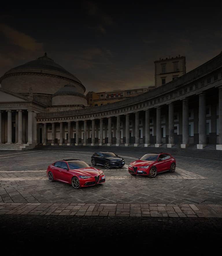 Three 2025 Alfa Romeo Intensa European models in a courtyard. From left to right: a red Stelvio Intensa, a black Tonale Intensa and a red Giulia Intensa.