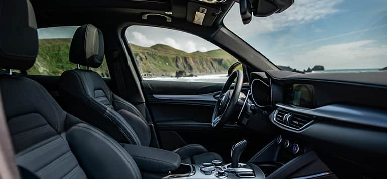 Los asientos delanteros, el volante y la pantalla táctil de Uconnect en el Alfa Romeo Stelvio 2026.
