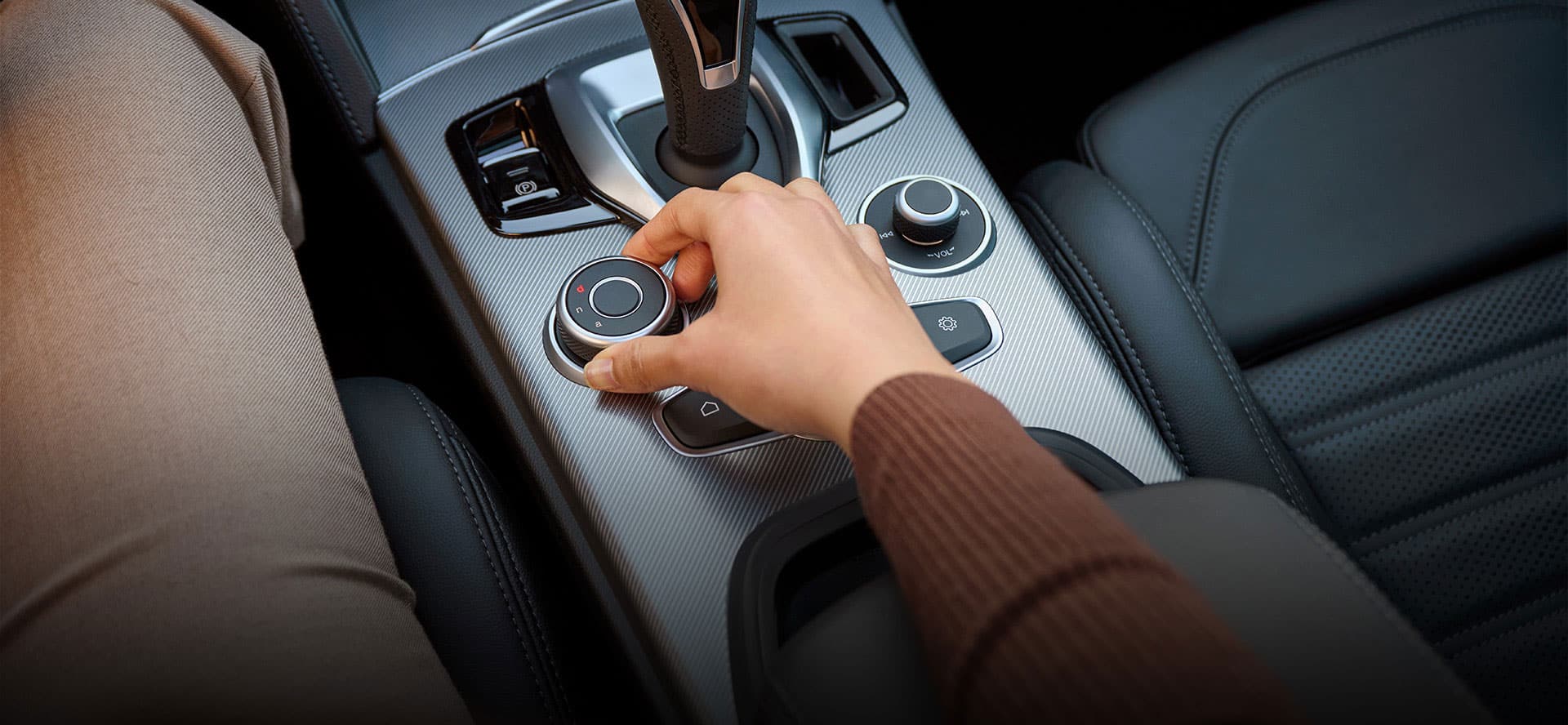 Driver adjusting the 2026 Alfa Romeo Stelvio's DNA Drive Mode Selector between Dynamic, Natural, and Advanced Efficiency modes