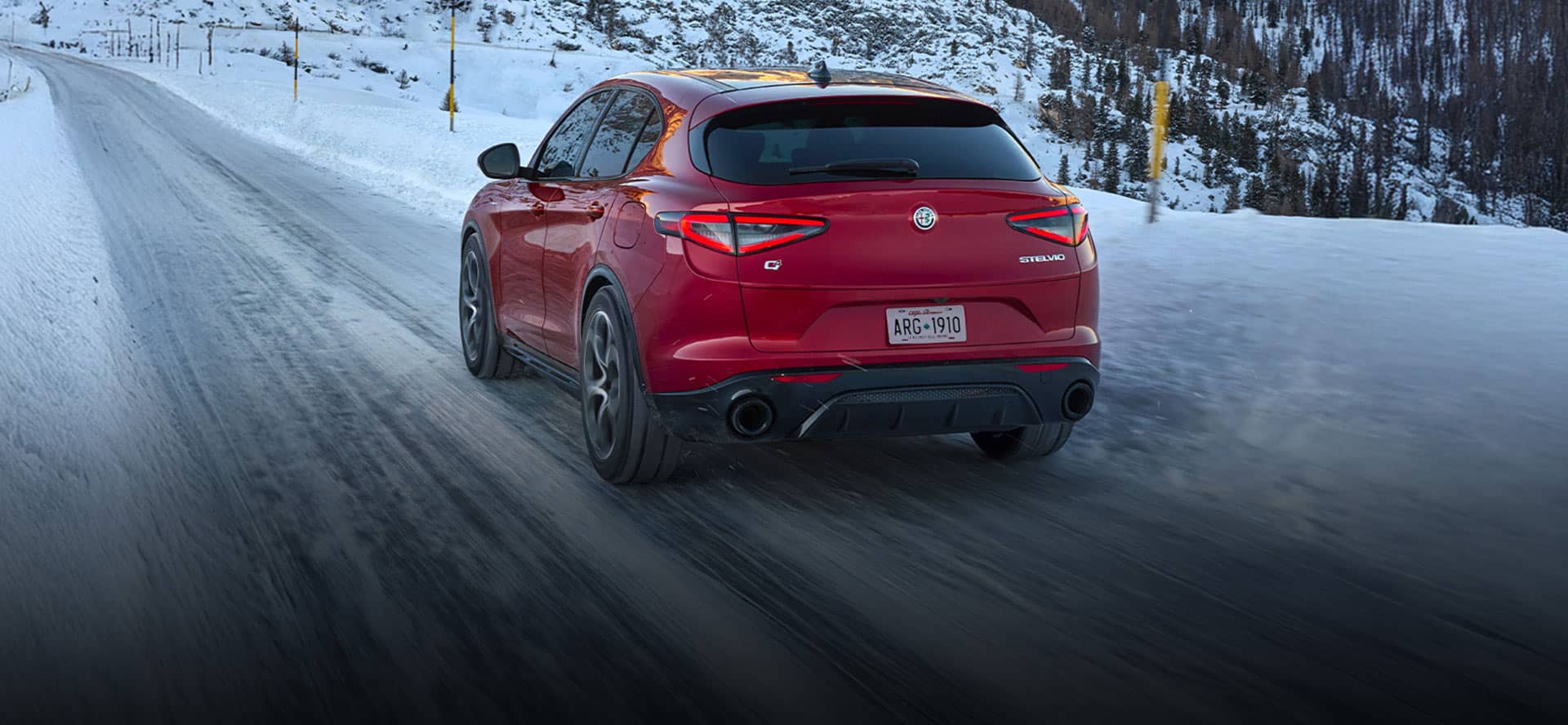 2026 Alfa Romeo Stelvio driving confidently on a snow-covered mountain road with standard Q4 all-wheel drive