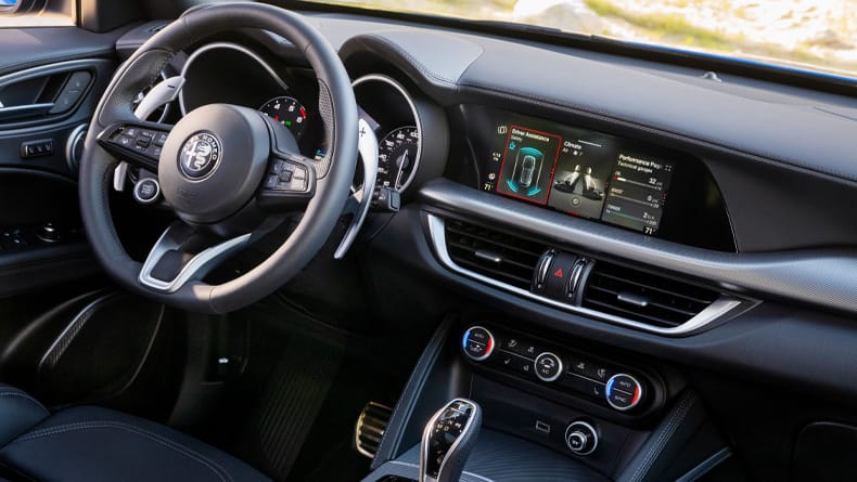 El volante, la pantalla táctil de Uconnect, las aberturas de calefacción y refrigeración, y los controles de la consola central en un Alfa Romeo Stelvio 2026.
