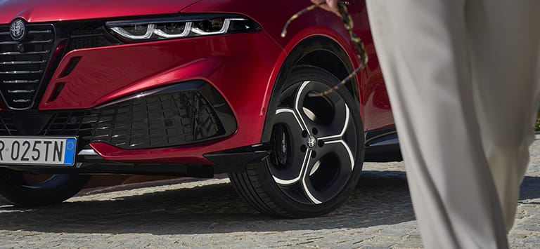 A front wheel and tire on a red 2026 Alfa Romeo Tonale Sport Speciale.
