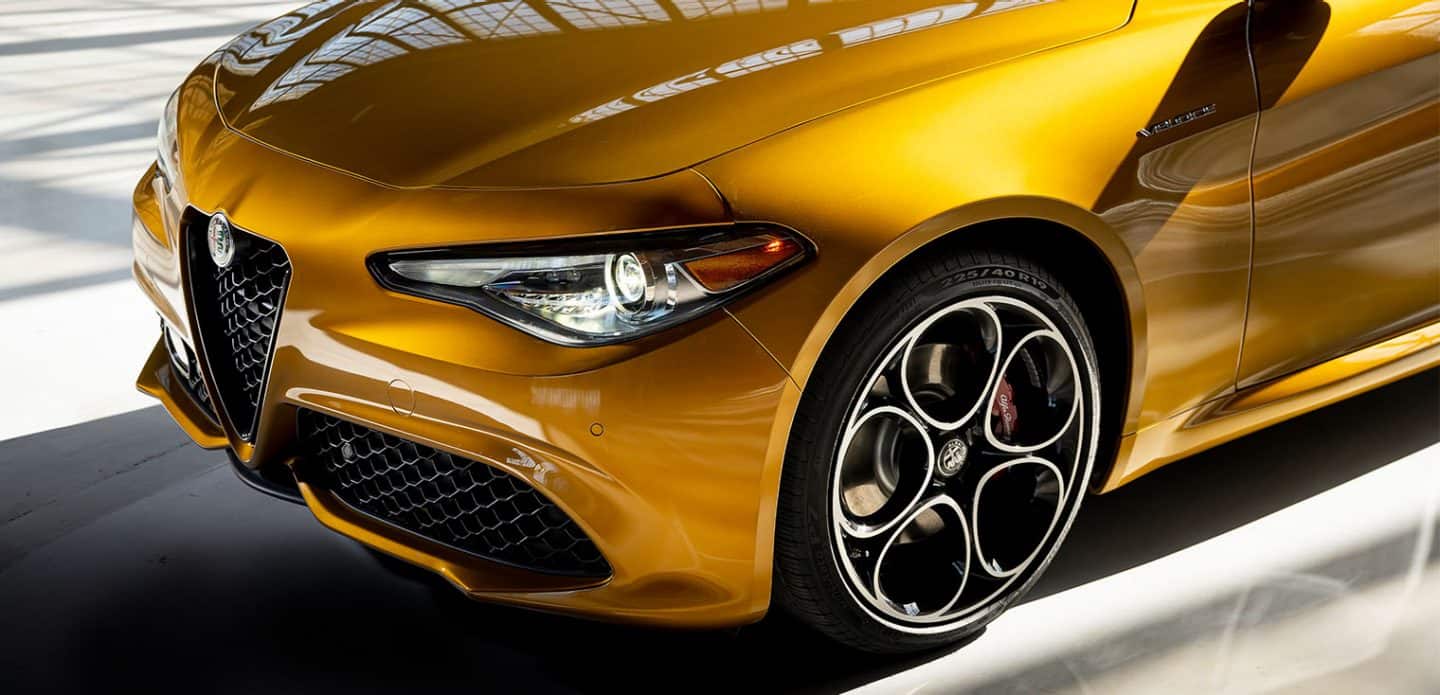 Display The front end and driver side wheel of a gold 2023 Alfa Romeo Giulia Veloce.