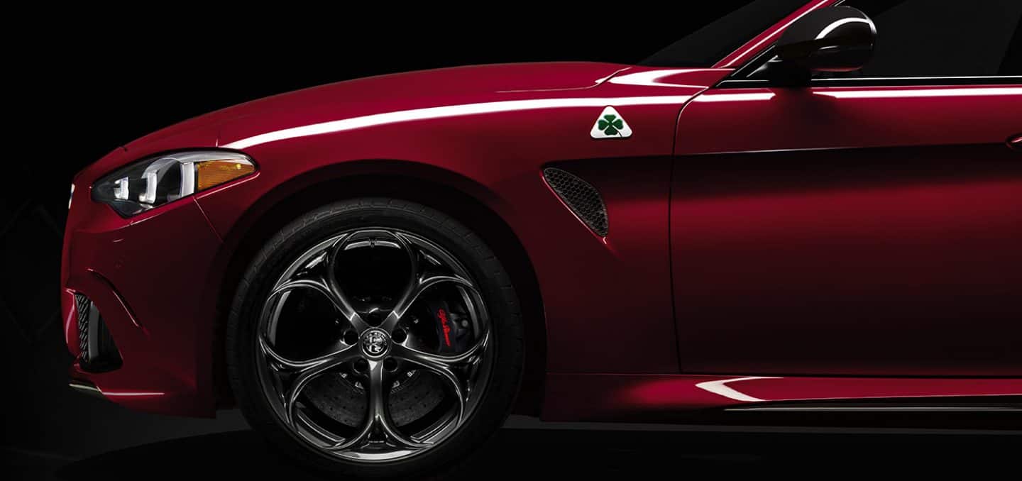 Display A partial driver-side profile—from the front end to the end of the driver's door—of a red 2024 Alfa Romeo Giulia Quadrifoglio.