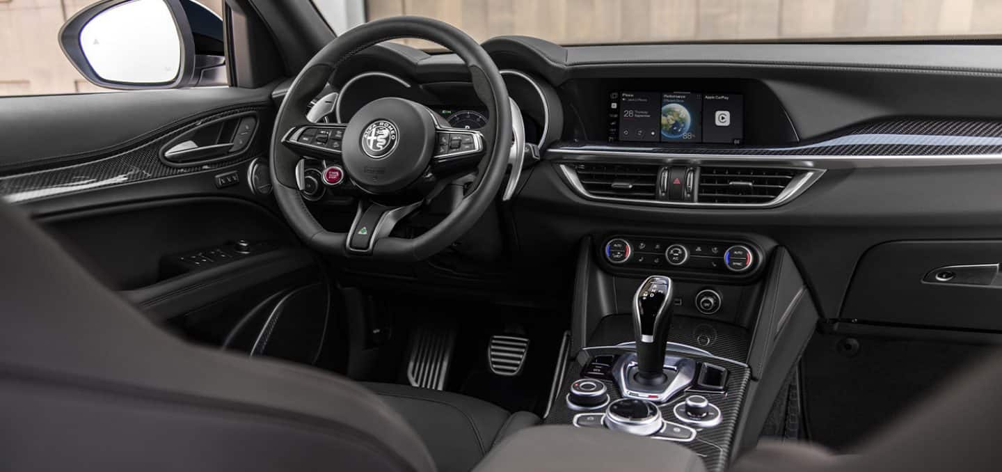 Display The interior of the 2024 Alfa Romeo Stelvio TBD focusing on the steering wheel, center stack and multitouch display.