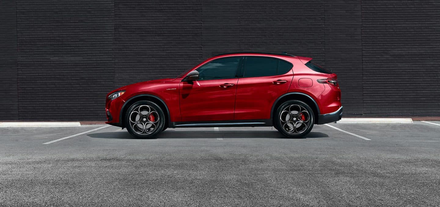 Display A driver-side profile of red 2024 Alfa Romeo Stelvio TBD parked across two spots.