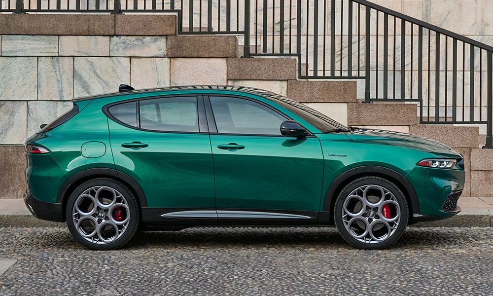 A profile view of a green 2023 Alfa Romeo Tonale parked inside a building with an abstract design on the wall.